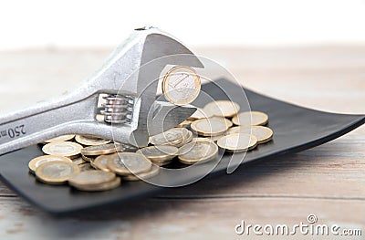 A plate of euro coins and a pair of pliers holding a coin Stock Photo