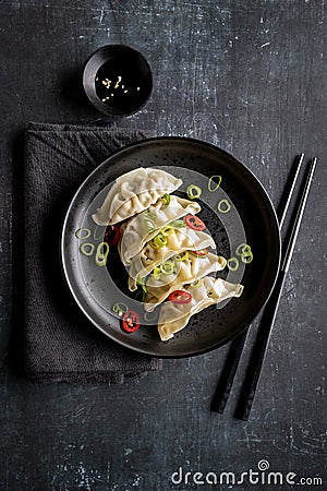 A plate with fresh gyoza dumpling on black plate and background with chopsticks Stock Photo