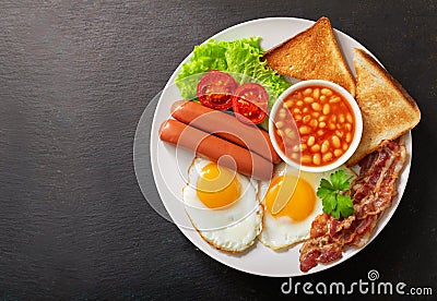 plate of fried eggs with bacon beans sausages toasts and tomatoes top view Stock Photo