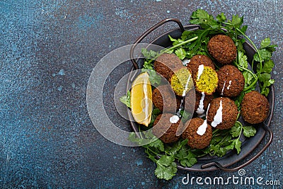 Plate of fried falafel balls served with fresh green cilantro and lemon top view on rustic concrete background Stock Photo