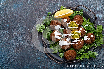 Plate of fried falafel balls served with fresh green cilantro and lemon top view on rustic concrete background Stock Photo