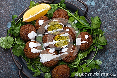 Plate of fried falafel balls served with fresh green cilantro and lemon, top view on rustic concrete background Stock Photo