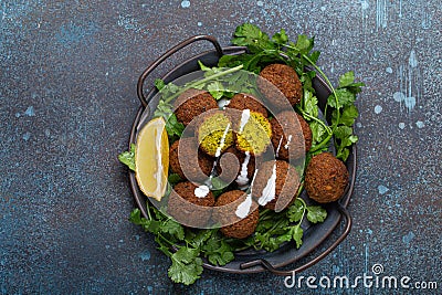 Plate of fried falafel balls served with fresh green cilantro and lemon, top view on rustic concrete background Stock Photo