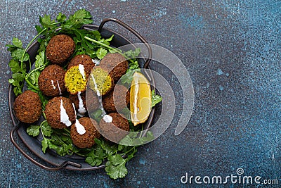 Plate of fried falafel balls served with fresh green cilantro and lemon top view on rustic concrete background Stock Photo