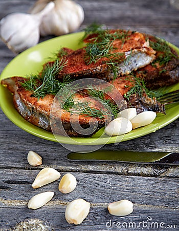 Plate with fried fish and garlic on a table Stock Photo