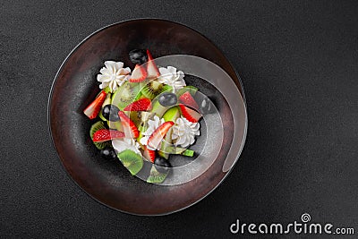 Plate with fruit salad, kiwi, strawberries, blueberries, apple, whipped cream Stock Photo