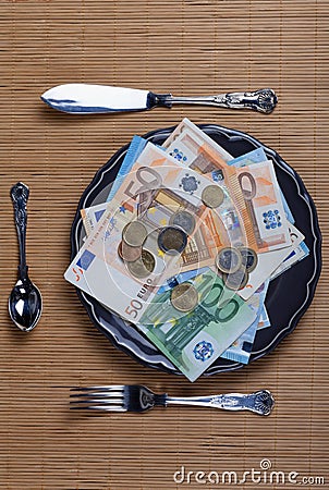 A plate full of money ready to be eaten with cutlery Stock Photo