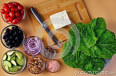 A plate with green salad leaves and a cutting board with feta cheese and a knife next to it. Seven bowls with tomatoes, black Stock Photo