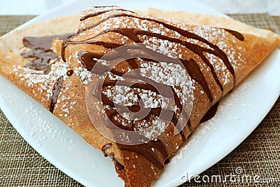 Plate of Mouthwatering French Crepe with Chocolate Sauce and Icing Sugar Stock Photo