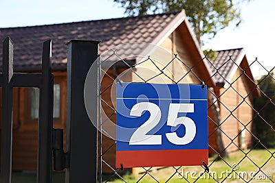 Plate with number twenty five hanging on fence near houses outdoors Stock Photo