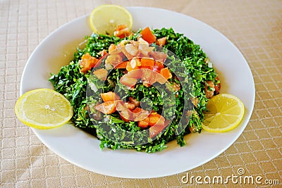 Plate of parsley and tomato tabbouleh with lemon wedges Stock Photo