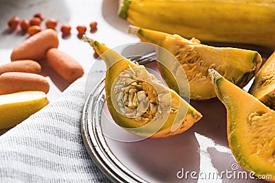 Plate with pumpkin quarters on striped towel. Stock Photo
