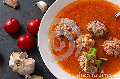 1 plate of red tomato soup with meatballs, garlic and cilantro on a black background close up, fresh cherry Stock Photo