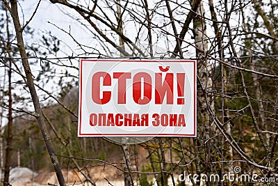 A plate with the text in Russian: Stop! Exclusion zone! Banner on barbed wire in dangerous and protected area. Stop forbidden sign Editorial Stock Photo