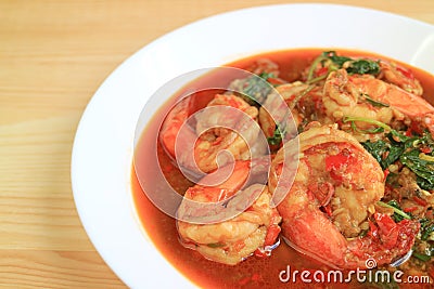 Plate of Thai Style Spicy Stir Fried Prawns with Holy Basil Served on Wooden Table Stock Photo