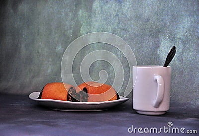 A plate with three poppy seed buns and a cup of hot drink with a spoon on a gray abstract background Stock Photo