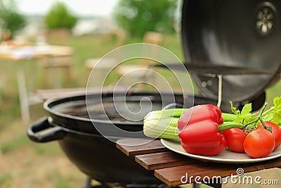 Plate with vegetables near barbecue grill outdoors Stock Photo