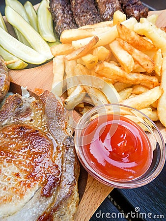 Plateau with assorted grilled pork dishes fries pickles and sauces Stock Photo