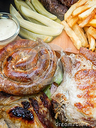 Plateau with assorted grilled pork dishes fries pickles and sauces Stock Photo