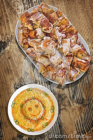 Plateful Of Roasted Pork Meat With Bowl Of Garnished Russian Salad Set On Old Weathered Wooden Garden Table Stock Photo