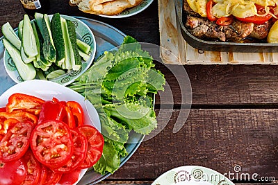 Plates with chopped tomatoes, cucumbers and a dish with baked potatoes Stand on a wooden table Stock Photo