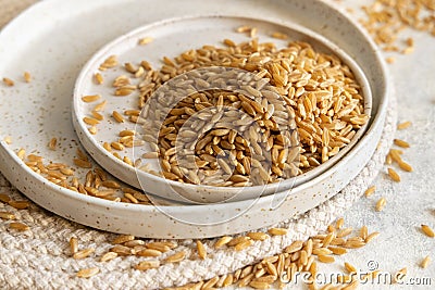 Plates of raw dry rye grain on white table close up. Healthy alternative low gluten diet Stock Photo