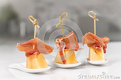 Plates with skewers made of melon bits with cured ham on a table Stock Photo