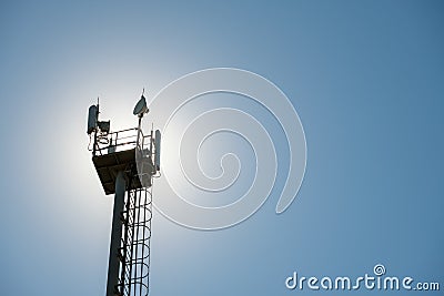 Platform on a cell phone mast with fences and transmitters, against the backdrop of the sun on a summer day Stock Photo