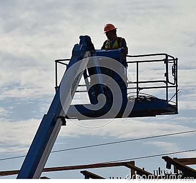 A platform lift raises a worker above a bridge Editorial Stock Photo