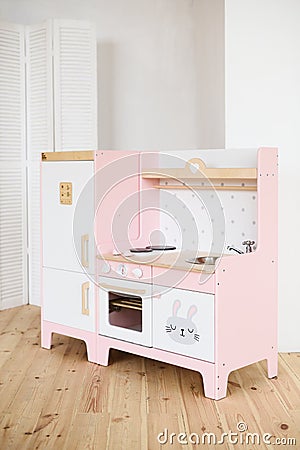 Play furniture for children. Sweet little pink kitchen with fridge, stove, oven and sink in light room Stock Photo