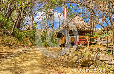 PLAYA MONTEZUMA, COSTA RICA, JUNE, 28, 2018: Outdoor view of thatched roof over sandy beach and gorgeous blue sky in Editorial Stock Photo