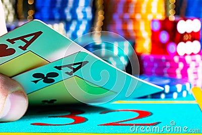 Player lifts the playing cards lying on the blue gaming table in the casino. Man's hand revealing pair of aces Stock Photo