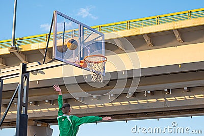 A player throws a ball into a basketball basket Editorial Stock Photo