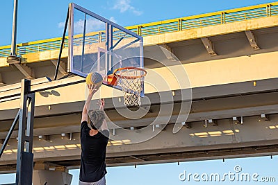 A player throws a ball into a basketball basket Editorial Stock Photo