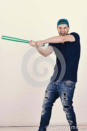 Player with wild face plays baseball. Guy in dark blue tshirt holds bright green bat Stock Photo