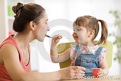 Playful baby girl spoon feeding her mother Stock Photo