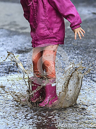 Child outdoor jump into puddle in boot after rain Stock Photo