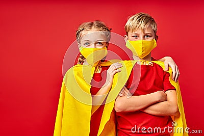 Playful children in heroes cloaks and medical masks posing Stock Photo