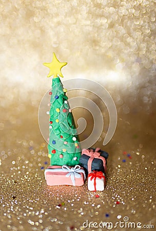 Playful clay christmas concept. Colorful handmade miniature Christmas tree and presents in gold background Stock Photo