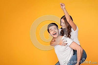 Playful couple in piggyback style making superman sign Stock Photo