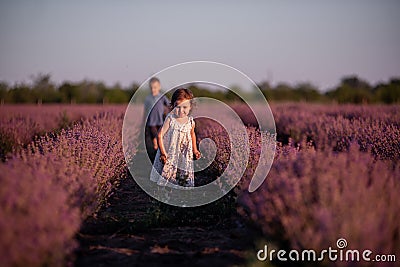 Playful cute boy girl are playing in rows of lavender purple field at sunset. Small couple. Allergy Stock Photo