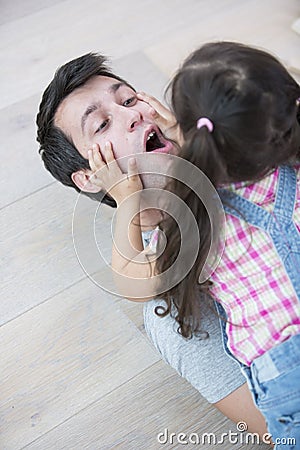 Playful daughter on top of father at home Stock Photo