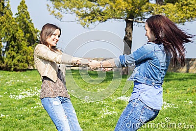 Playful friends holding hands and spinning in circles Stock Photo