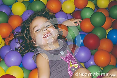 Playful girl lying in ball pit Stock Photo