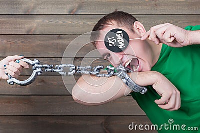 Playful handcuffed male shows funny icon on stick Stock Photo