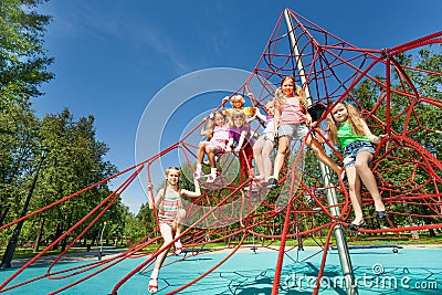 Playful kids sit on red ropes of playground Stock Photo