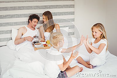 Playful siblings with parents on bed Stock Photo
