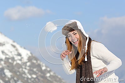 Playful woman throwing a snow ball in winter on holidays Stock Photo