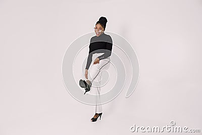 Playful young black girl smiling on light gray background with legs kicked out Stock Photo