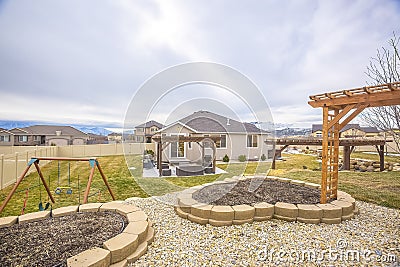 Playground and patio at the grassy yard of a home with wooden pergolas Stock Photo
